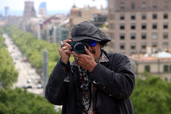 Johnny Depp, who plays a photojournalist in 'Minimata', holds a camera up to the press in Barcelona (by Pau Cortina)